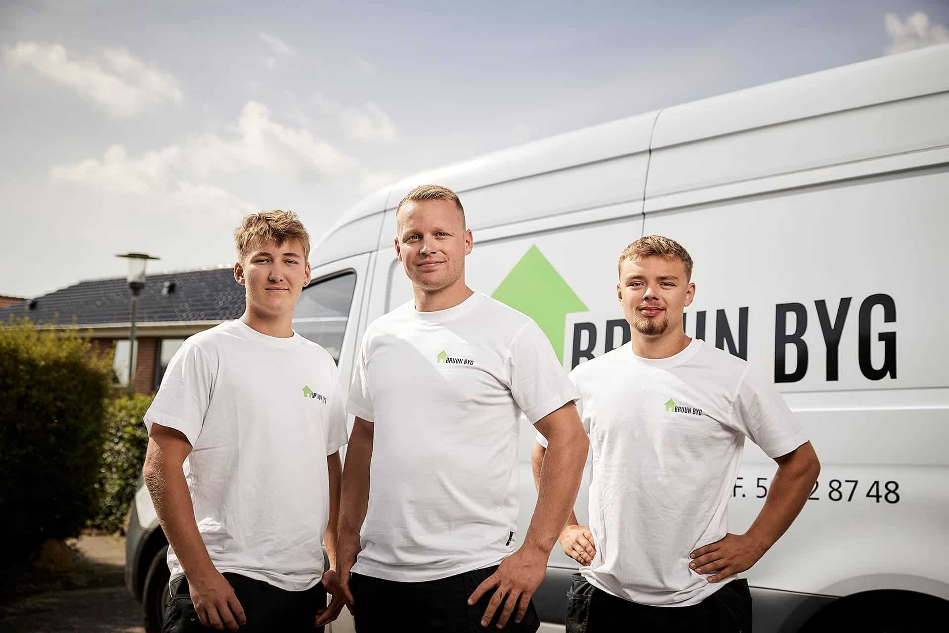 3 medarbejdere i uniform foran firmabil